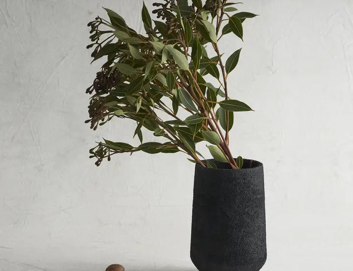 The Collective Pumice Vase, a matte black textured vase holding eucalyptus branches