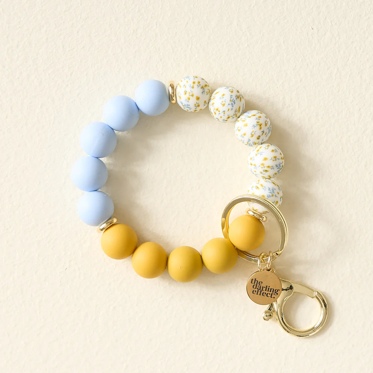 The Darling Effect Hands-Free Keychain Wristlet in Country Cottage, blue, floral and mustard silicone beads with a gold clasp