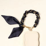 The Darling Effect Phone Scarf in Black attached to a cream phone case