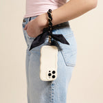 Woman in jeans carrying a phone on her wrist with The Darling Effect Phone Scarf in Black
