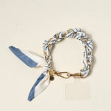 The Darling Effect Phone Scarf in Bluebell Stripe, a blue and white striped satin scarf on a gold chain wristlet