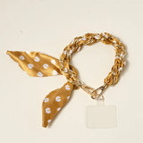 The Darling Effect Phone Scarf in Honey Blossom, a mustard floral satin scarf on a gold chain wristlet