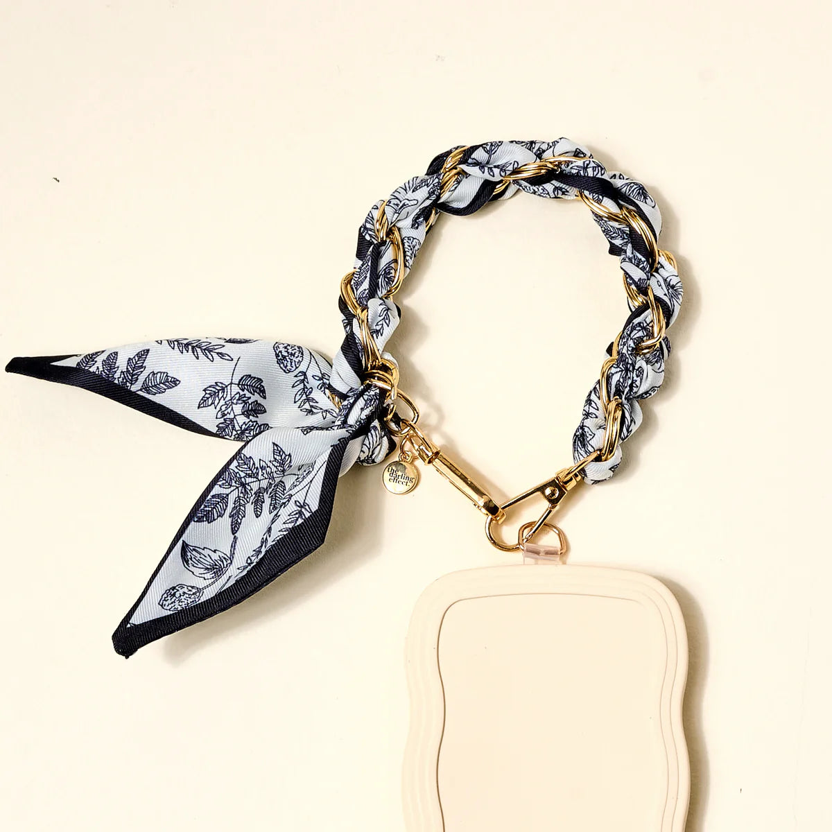 The Darling Effect Phone Scarf in Monochrome Muse attached to a cream phone case
