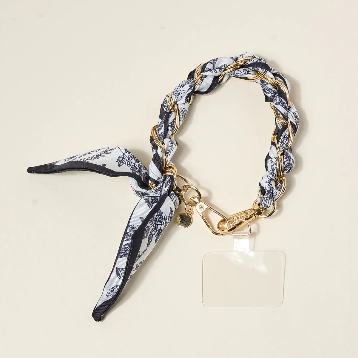 The Darling Effect Phone Scarf in Monochrome Muse, a black and white floral satin scarf on a gold chain wristlet