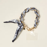 The Darling Effect Phone Scarf in Monochrome Muse, a black and white floral satin scarf on a gold chain wristlet