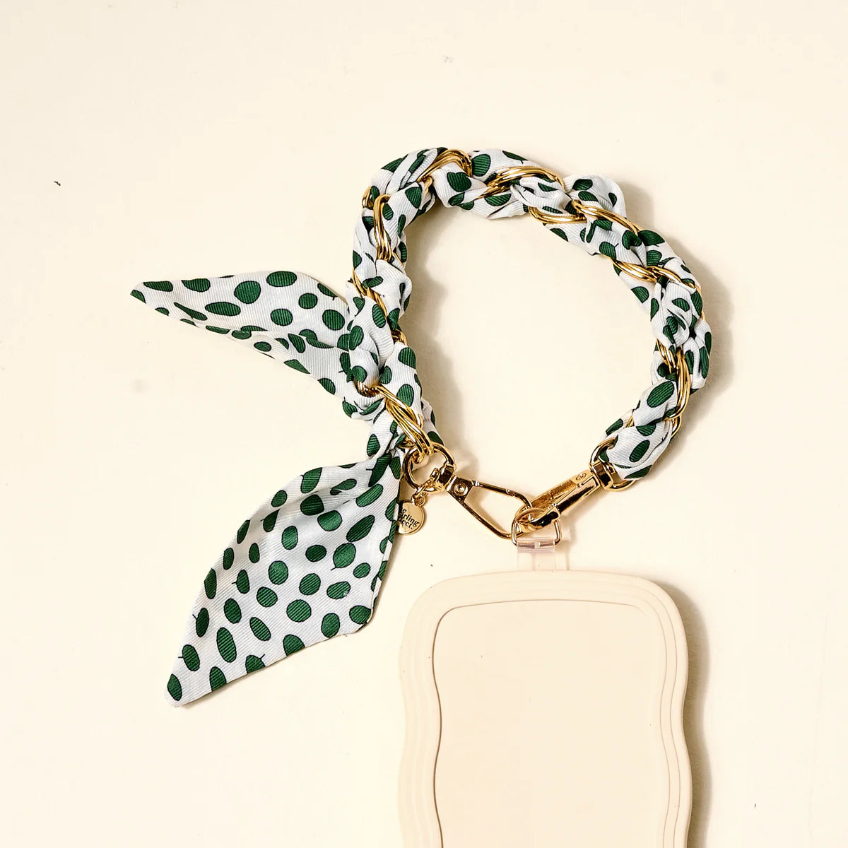 The Darling Effect Phone Scarf in Olive Dot attached to a cream phone case