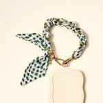 The Darling Effect Phone Scarf in Olive Dot attached to a cream phone case