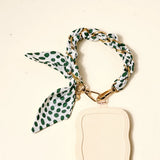 The Darling Effect Phone Scarf in Olive Dot attached to a cream phone case