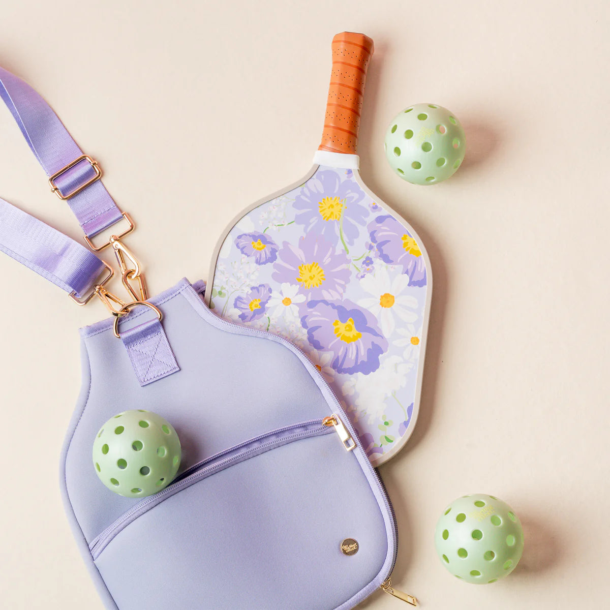 The Darling Effect Pickleball Paddle in Bouquet Beauty Purple with a lavender case and green pickleballs