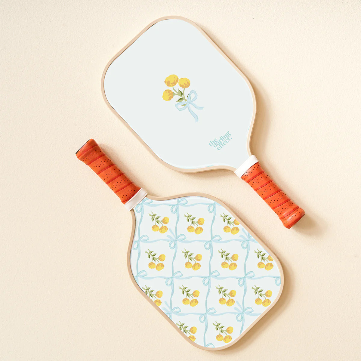 The Darling Effect Pickleball Paddle in Marigold Lane Blue, a white paddle with a yellow flower and blue trellis case