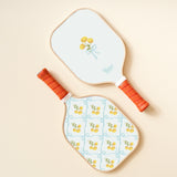 The Darling Effect Pickleball Paddle in Marigold Lane Blue, a white paddle with a yellow flower and blue trellis case