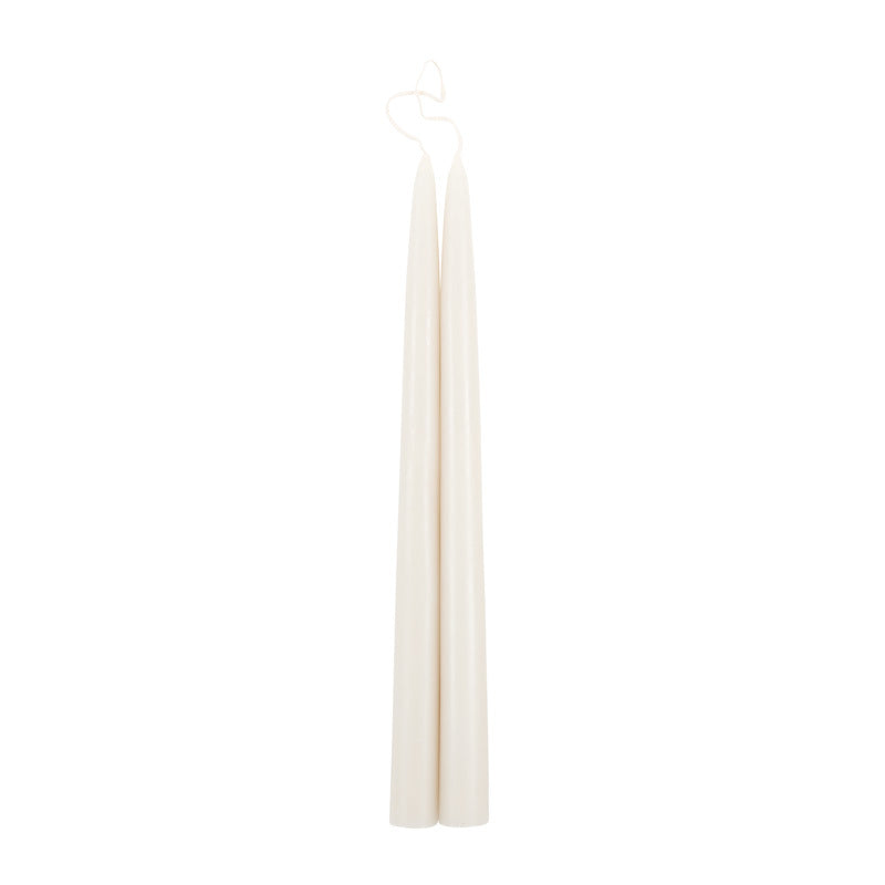 The Floral Society 18-inch Dipped Taper Candles in Parchment, a pair of ivory tapers hanging by their wick on white