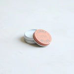 The Floral Society Candle Helper, a small silver tin of wax adhesive with a terracotta lid