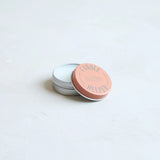 The Floral Society Candle Helper, a small silver tin of wax adhesive with a terracotta lid