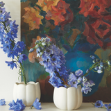 The Floral Society Ceramic Flower Frog Vases holding blue delphinium in front of a floral painting