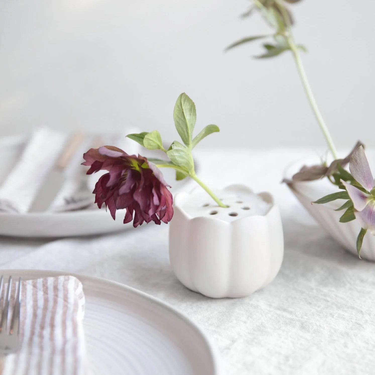 The Floral Society Ceramic Flower Frog Vases with single dark and pale flower stems on a table