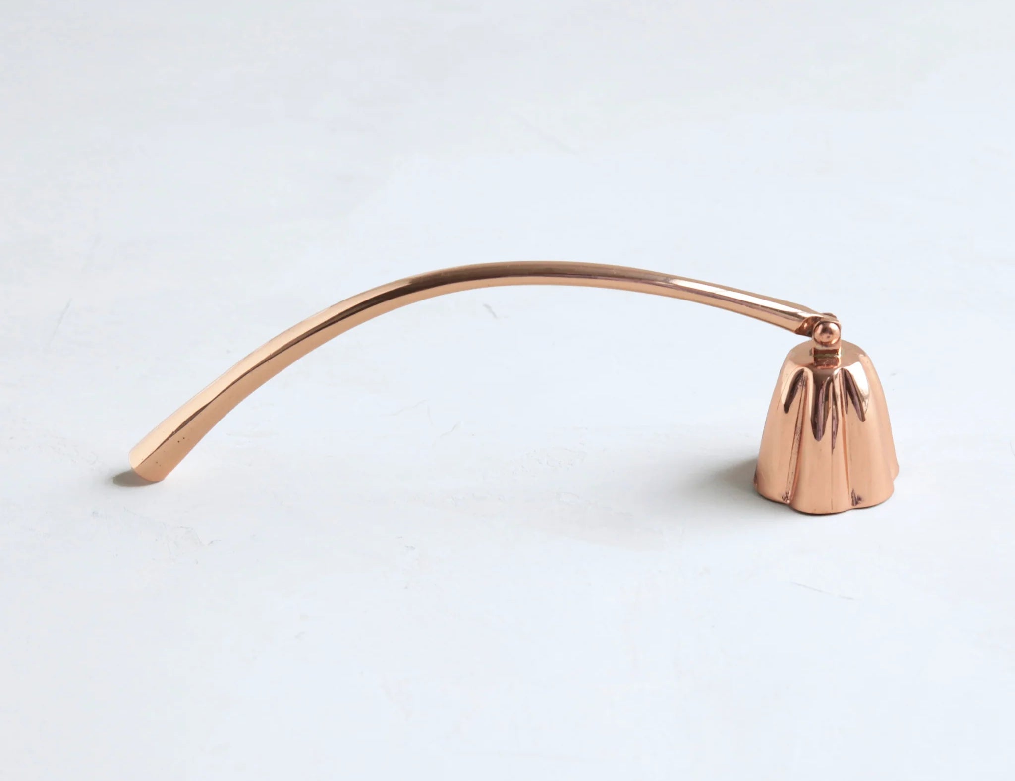 The Floral Society Copper Candle Snuffer, a curved copper handle with a bell-shaped snuffer