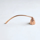 The Floral Society Copper Candle Snuffer, a curved copper handle with a bell-shaped snuffer