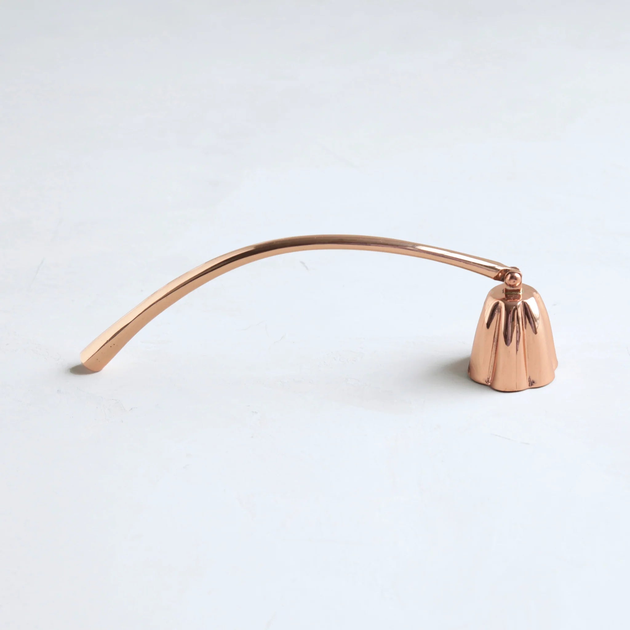 The Floral Society Copper Candle Snuffer, a curved copper handle with a bell-shaped snuffer