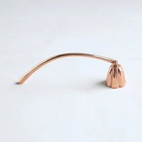 The Floral Society Copper Candle Snuffer, a curved copper handle with a bell-shaped snuffer