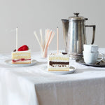 The Floral Society Wishing Candles in cream and blush on slices of cake at a table