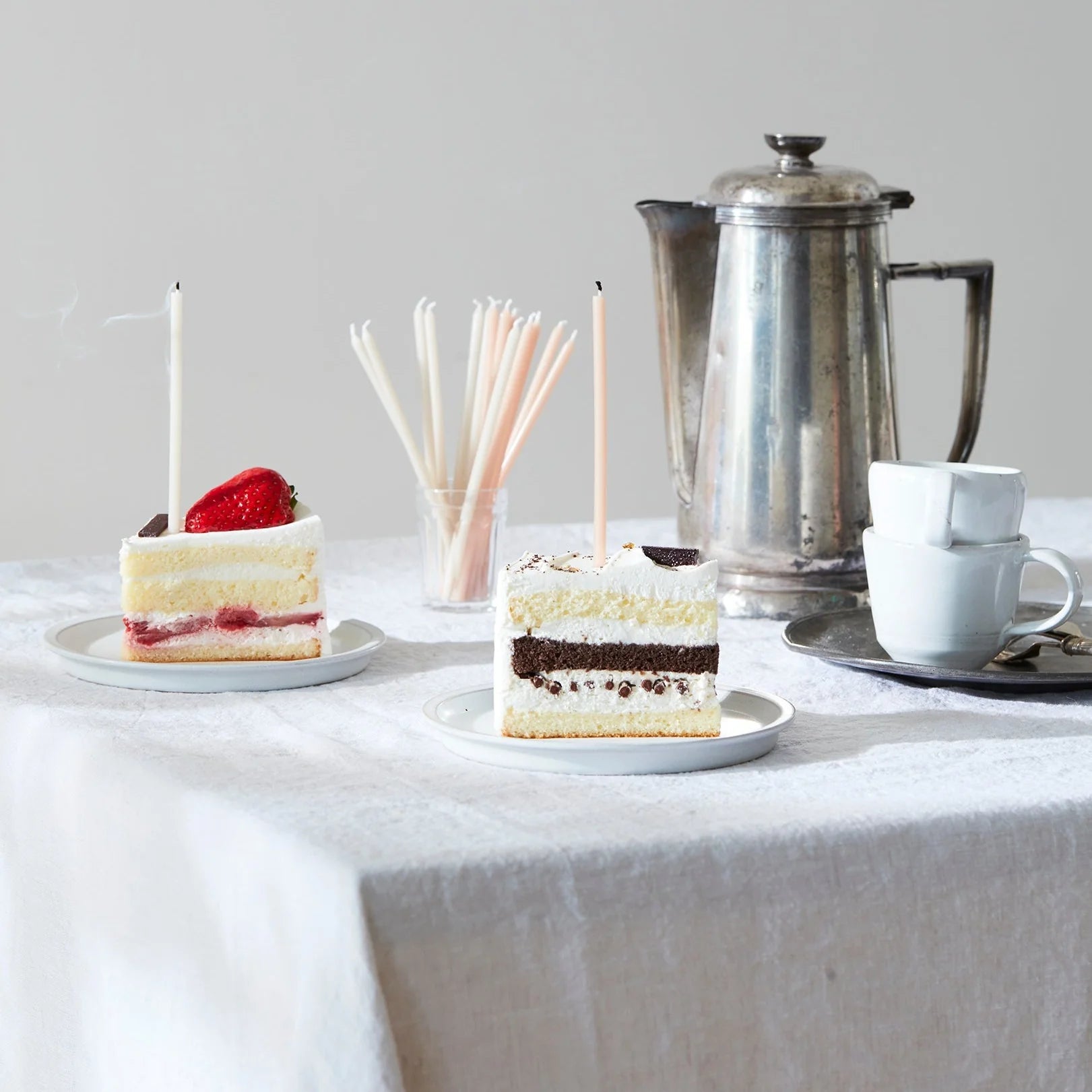 The Floral Society Wishing Candles in cream and blush on slices of cake at a table