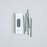 The Floral Society Wishing Candles in Moss, thin sage green taper candles beside their white box