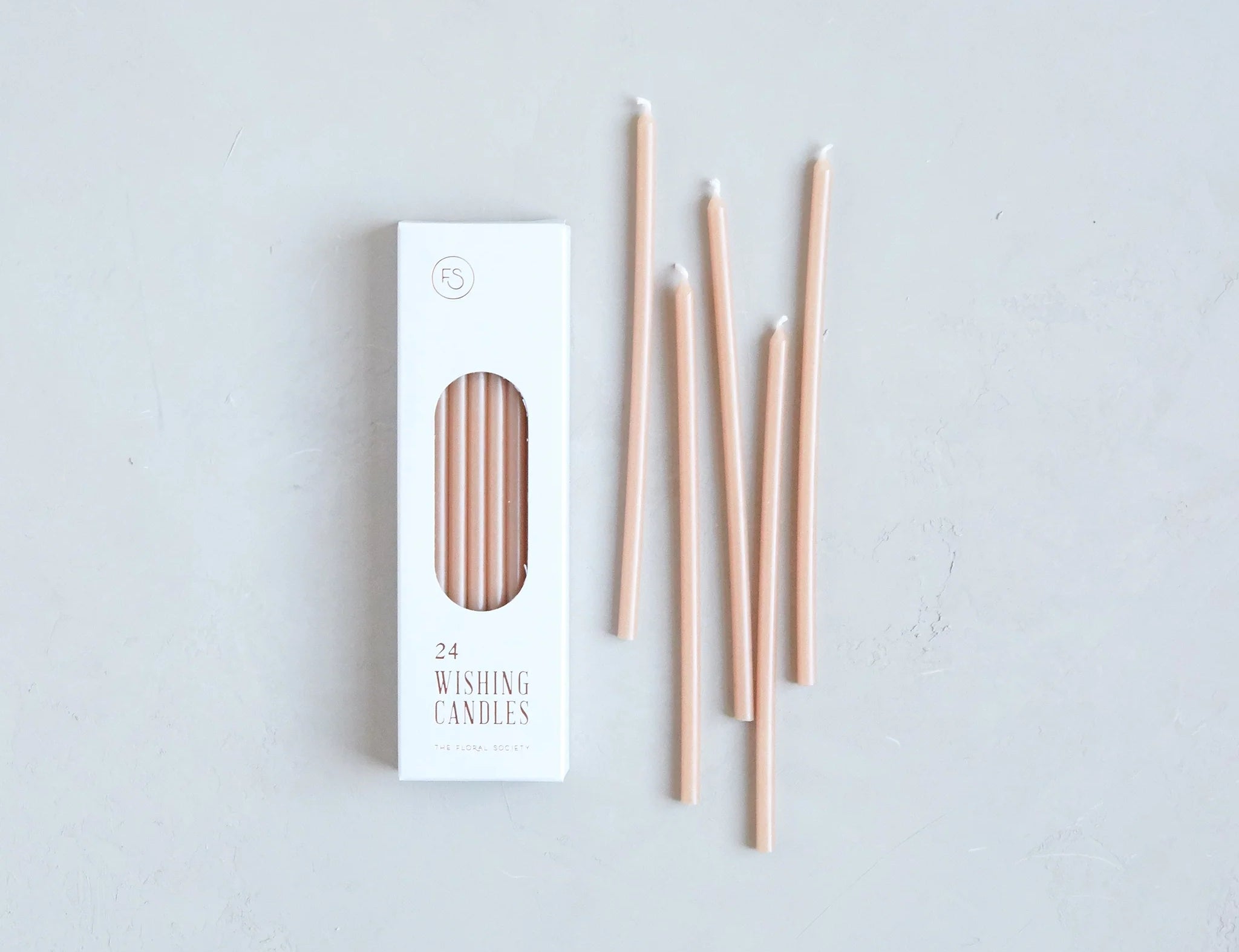 The Floral Society Wishing Candles in Petal, thin blush pink taper candles beside their white box