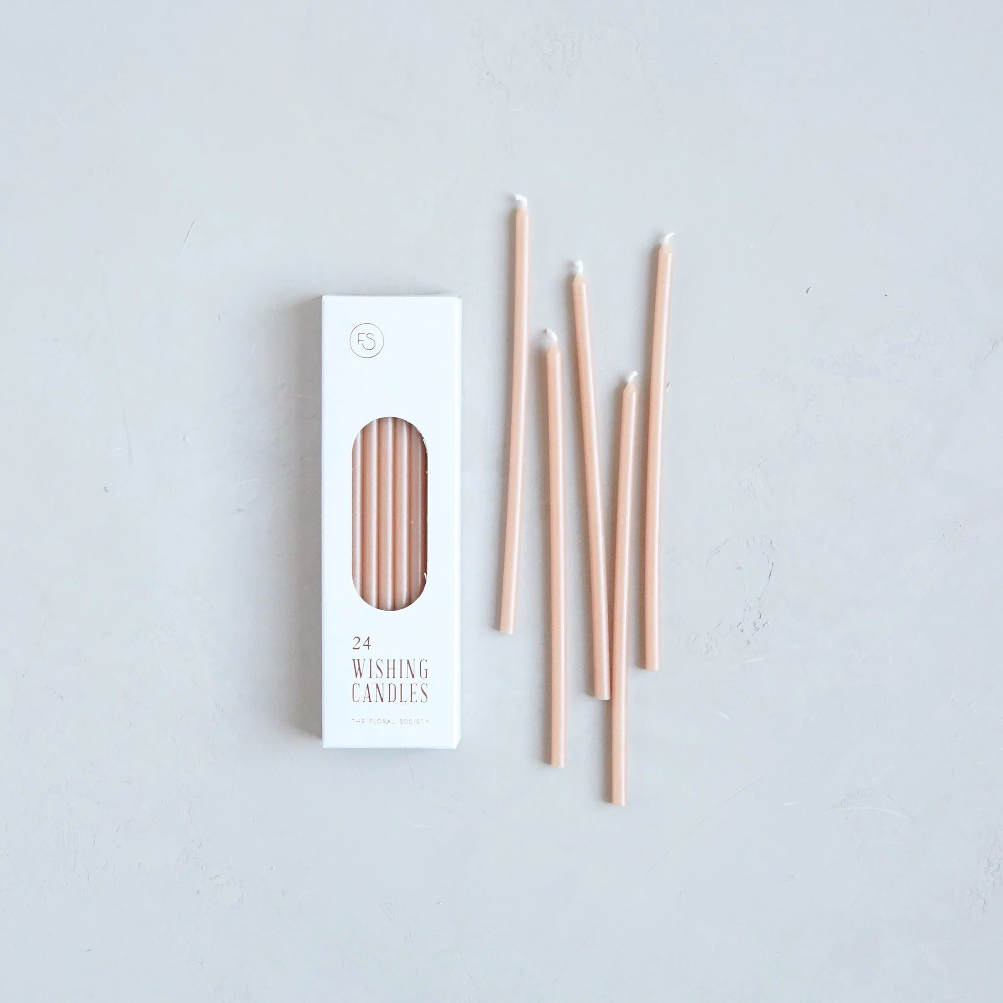 The Floral Society Wishing Candles in Petal, thin blush pink taper candles beside their white box