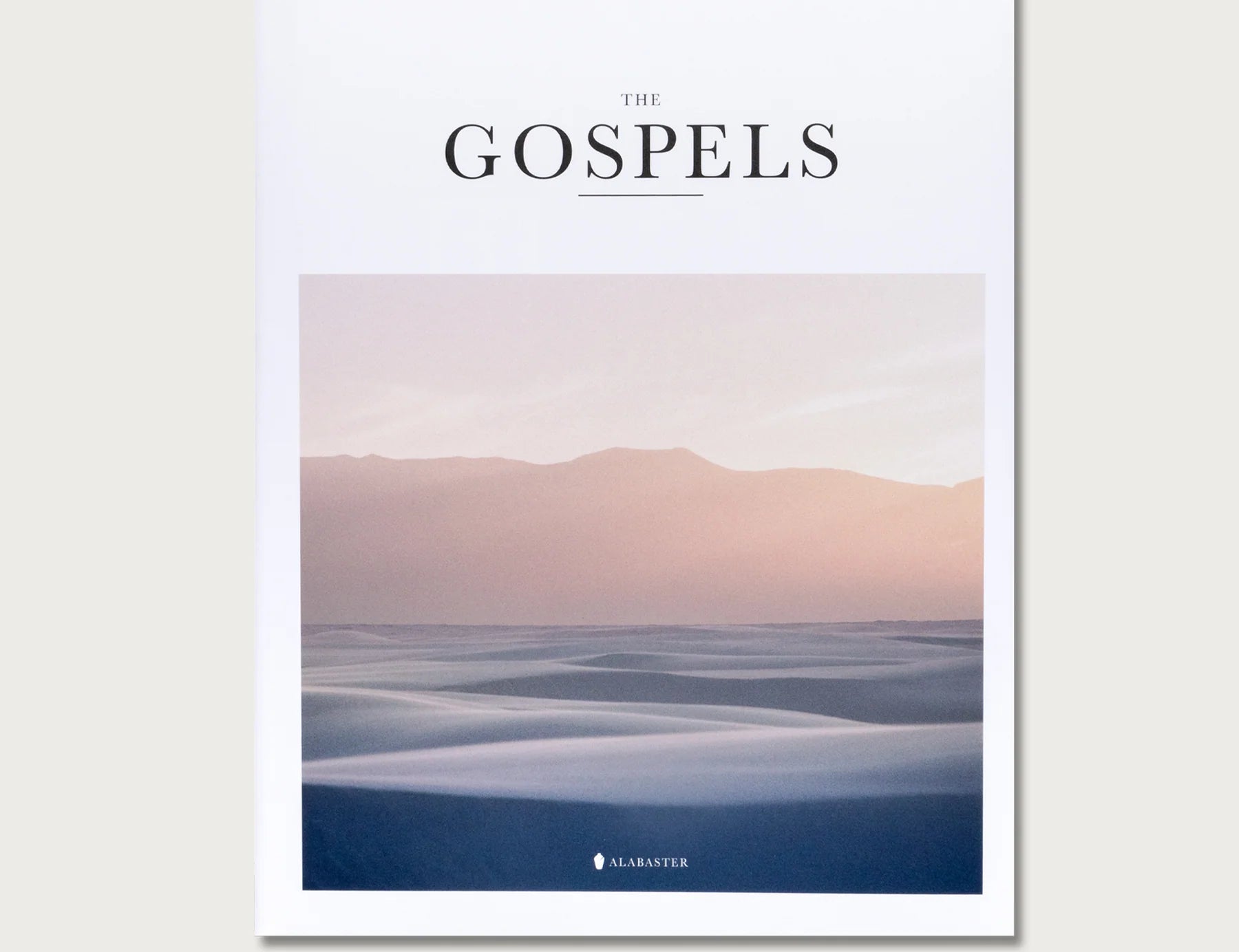 The Gospels book, a white cover with a soft pink and blue landscape photo