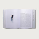The Gospels book open to a text page with a photo of a woman in a white room
