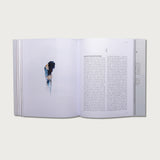 The Gospels book open to a text page with a photo of a woman in a white room