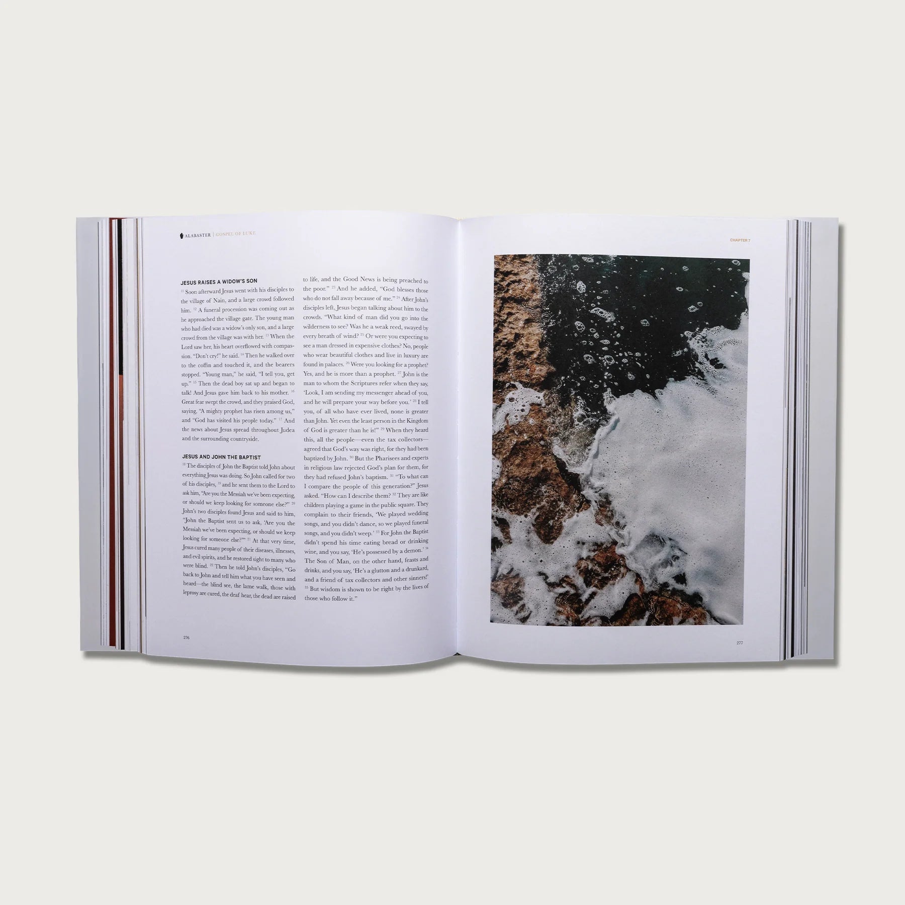 The Gospels book open to a text page with a photo of crashing waves