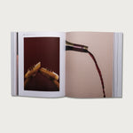 The Gospels book open to a spread with photos of a hand and pouring wine
