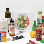 W&P Lunch Cookbook surrounded by pantry staples like hot honey, sea salt, olive oil and hot sauce