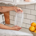 Hands stretching a W&P Reusable Stretch Lid over a glass bowl in a kitchen