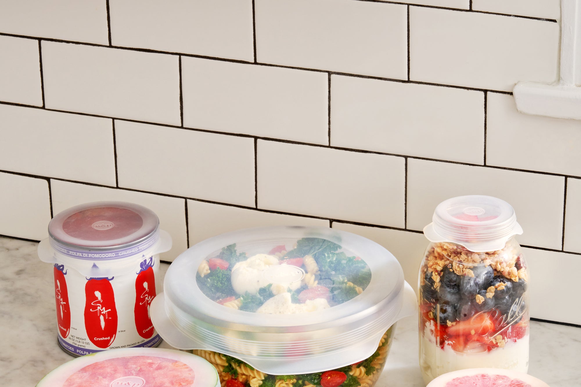 W&P Reusable Stretch Lids covering bowls of fruit and salad on a kitchen counter