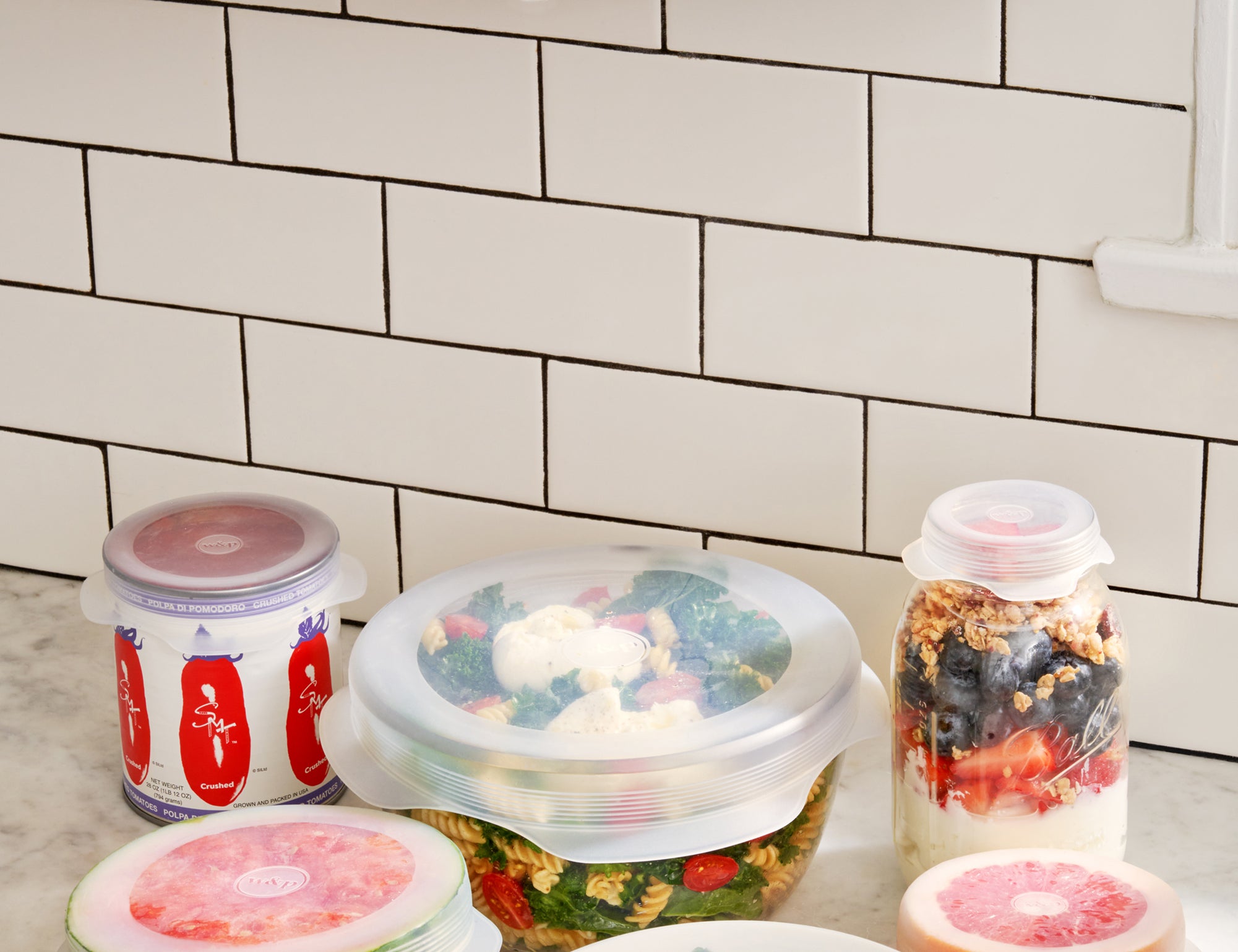 W&P Reusable Stretch Lids covering bowls of fruit and salad on a kitchen counter