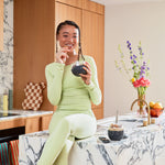 Smiling woman in green eating from a W&P Seal Tight Bowl in Terrazzo Charcoal at a marble counter