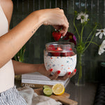 Hand adding strawberries to a W&P Seal Tight Bowl in Terrazzo Cream filled with yogurt