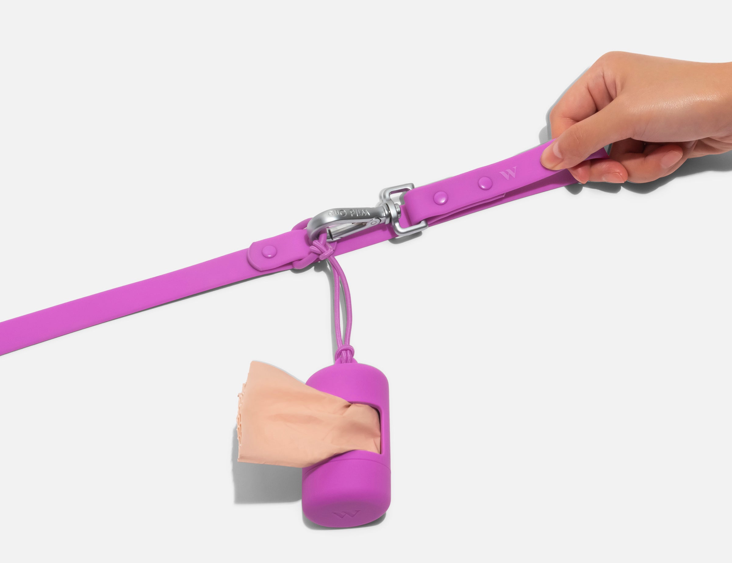 Wild One Dog Leash, second view, the orchid leash in hand with a matching poop bag carrier clipped on