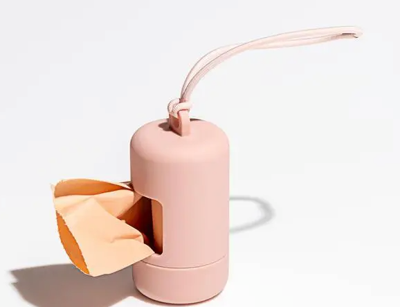 Wild One Poop Bag Carrier in blush pink with a waste bag dispensing — silicone dog poop bag holder